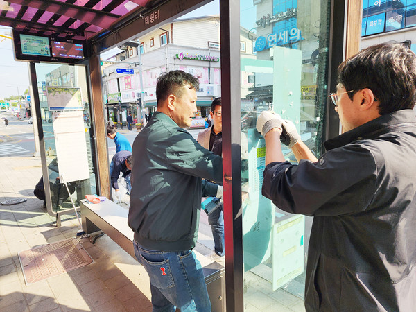 고광만 가납음주민자치회장(사진 왼쪽)과 기관단체장이 버스승강장 불법광고물을 떼어 내고 있다.